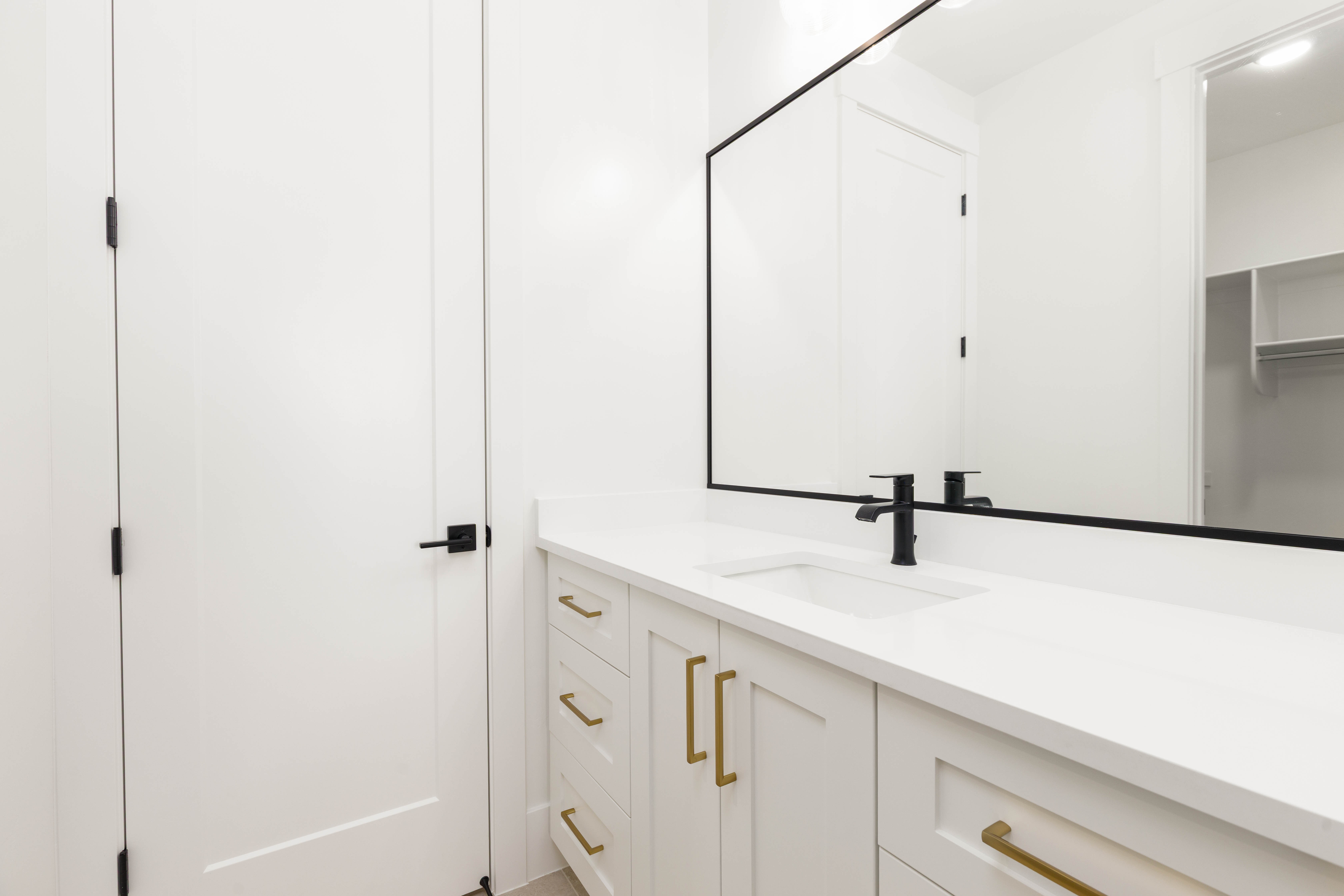 White vanity with gold-tone hardware, a white countertop, and an integrated rectangular sink