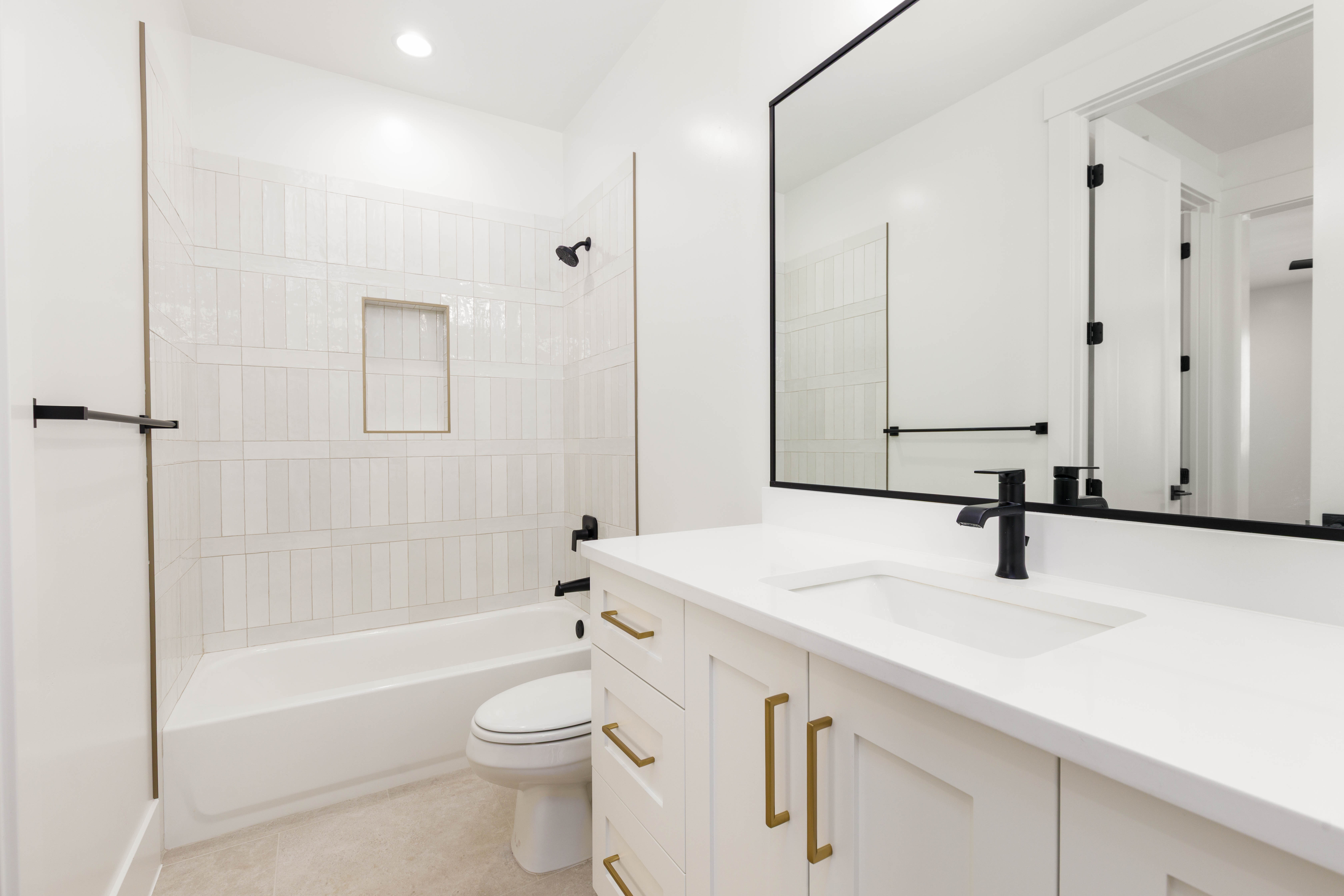 White bath vanity with integrated sink and matte black faucet, featuring a large framed mirror