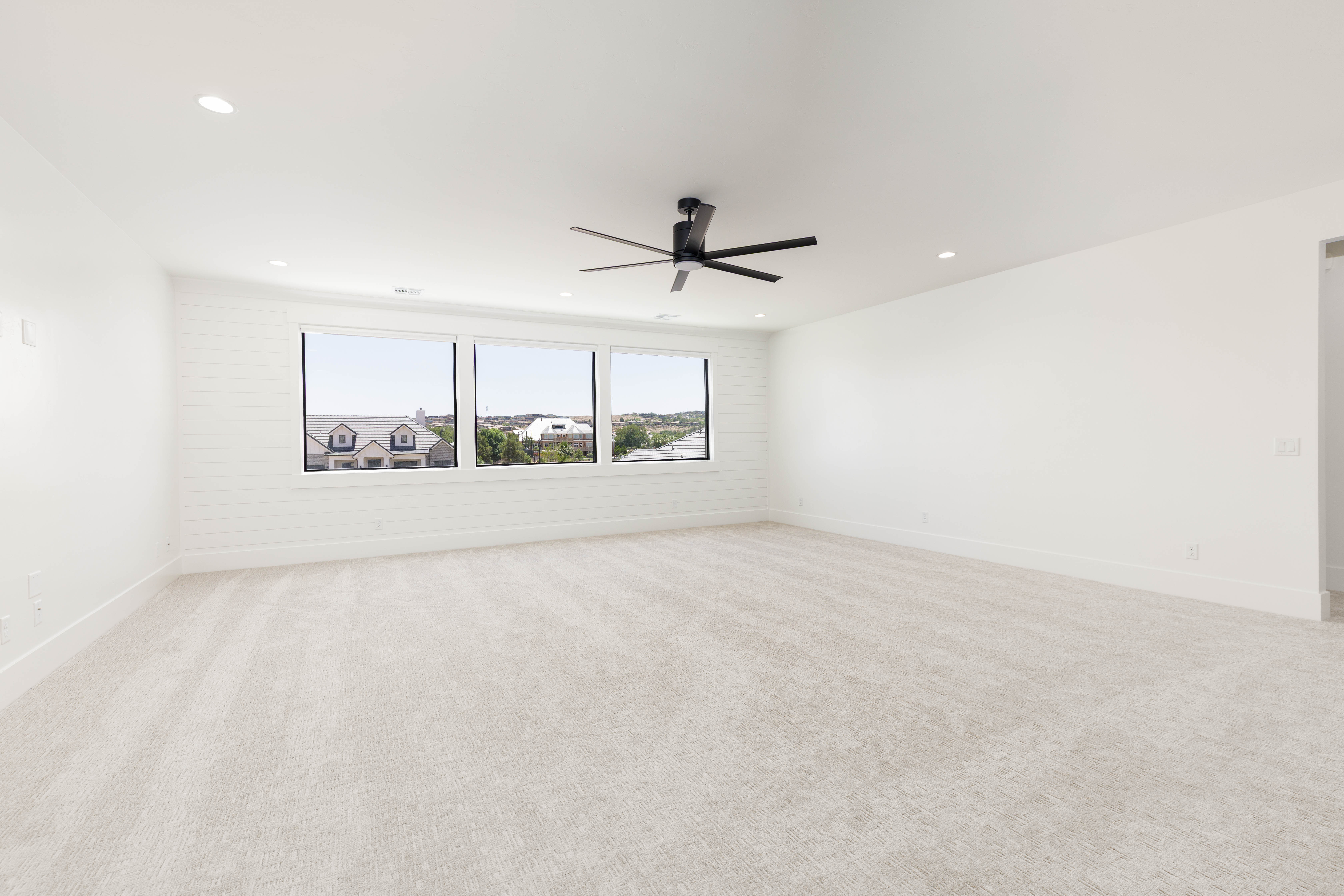 Spacious room featuring light-toned carpet flooring and recessed ceiling lighting