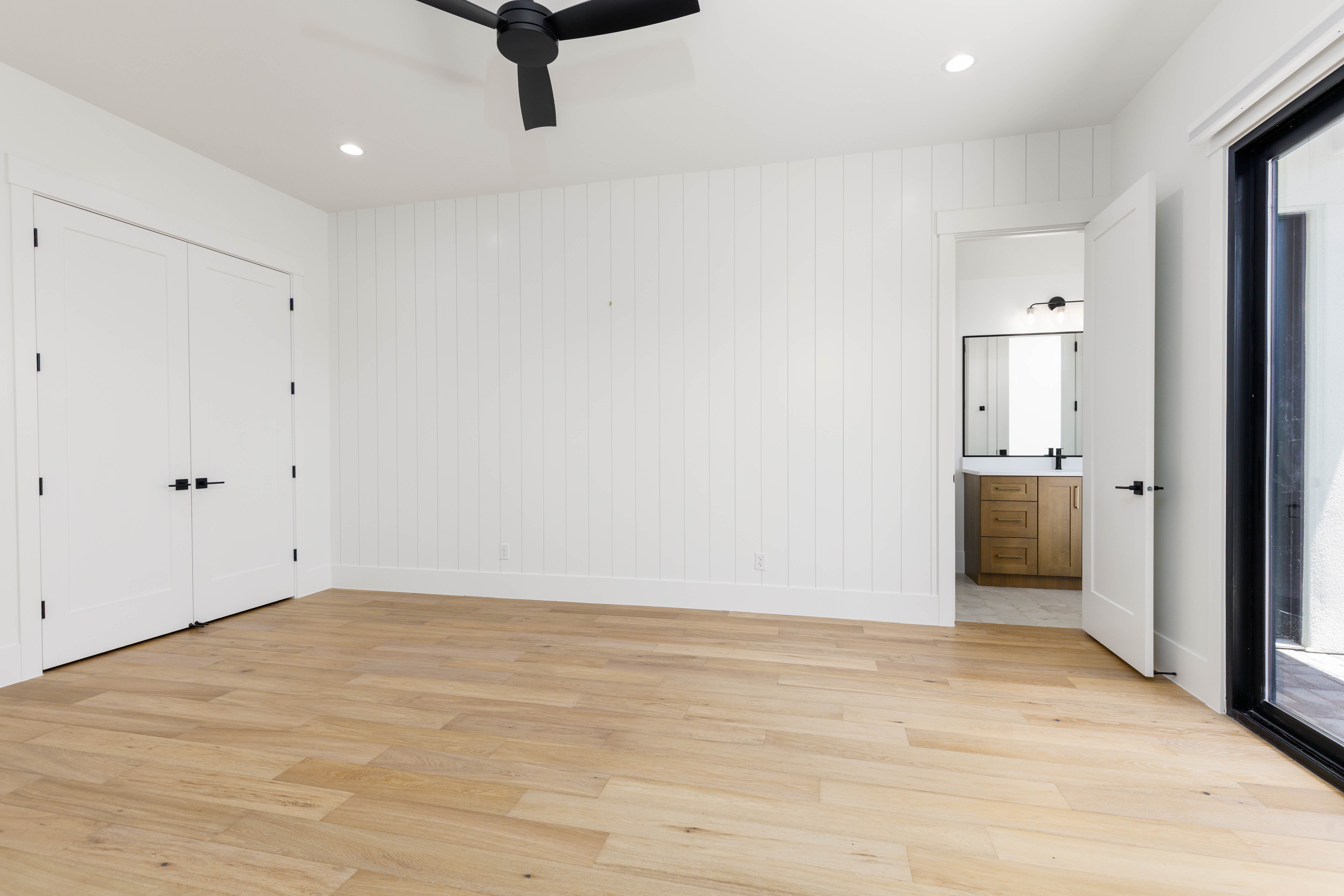 Spacious interior featuring wide plank wood-finish flooring, a white shiplap accent wall, and recessed lighting