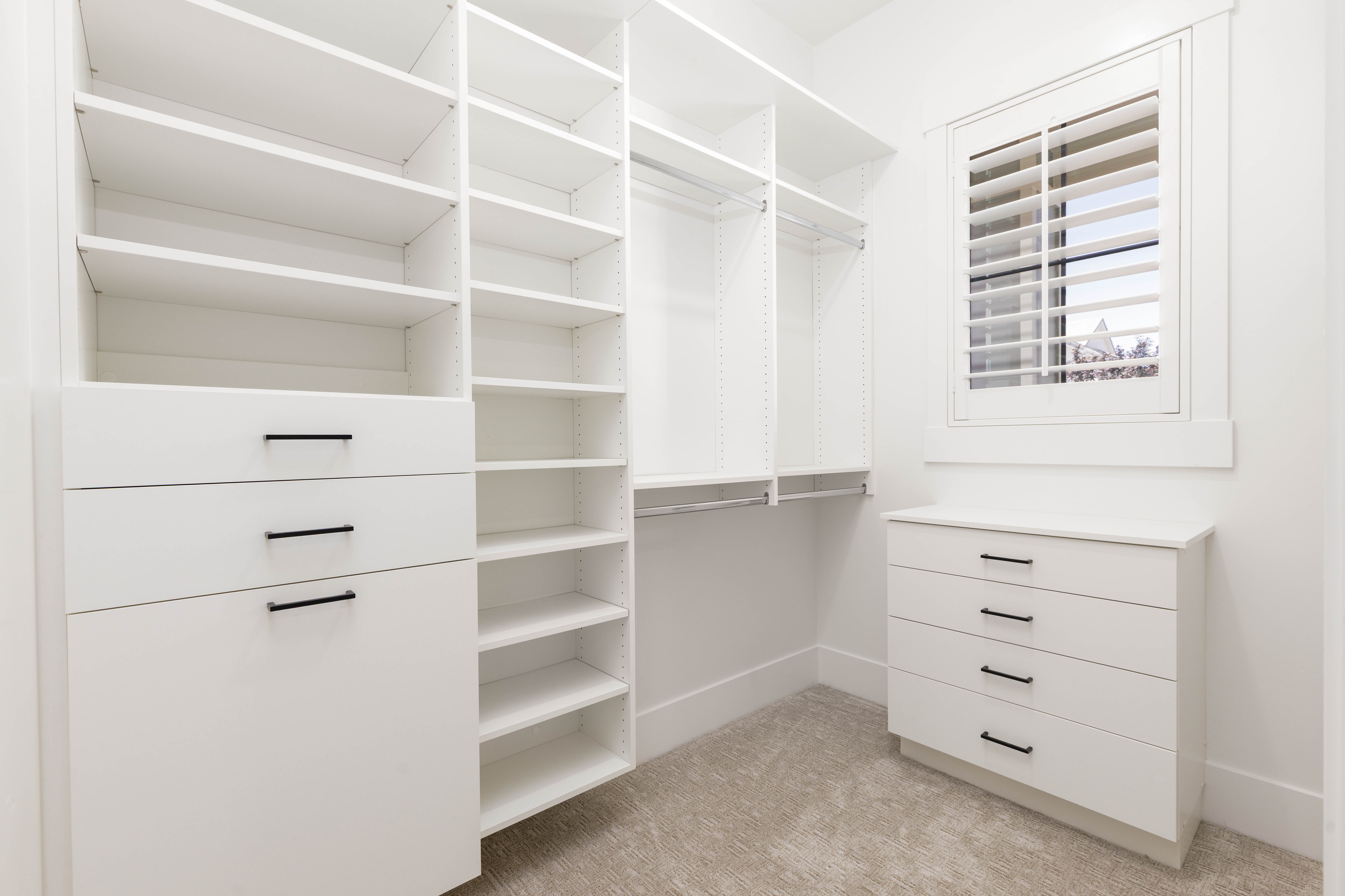 Custom closet system featuring extensive shelving and built-in drawers with matte black hardware