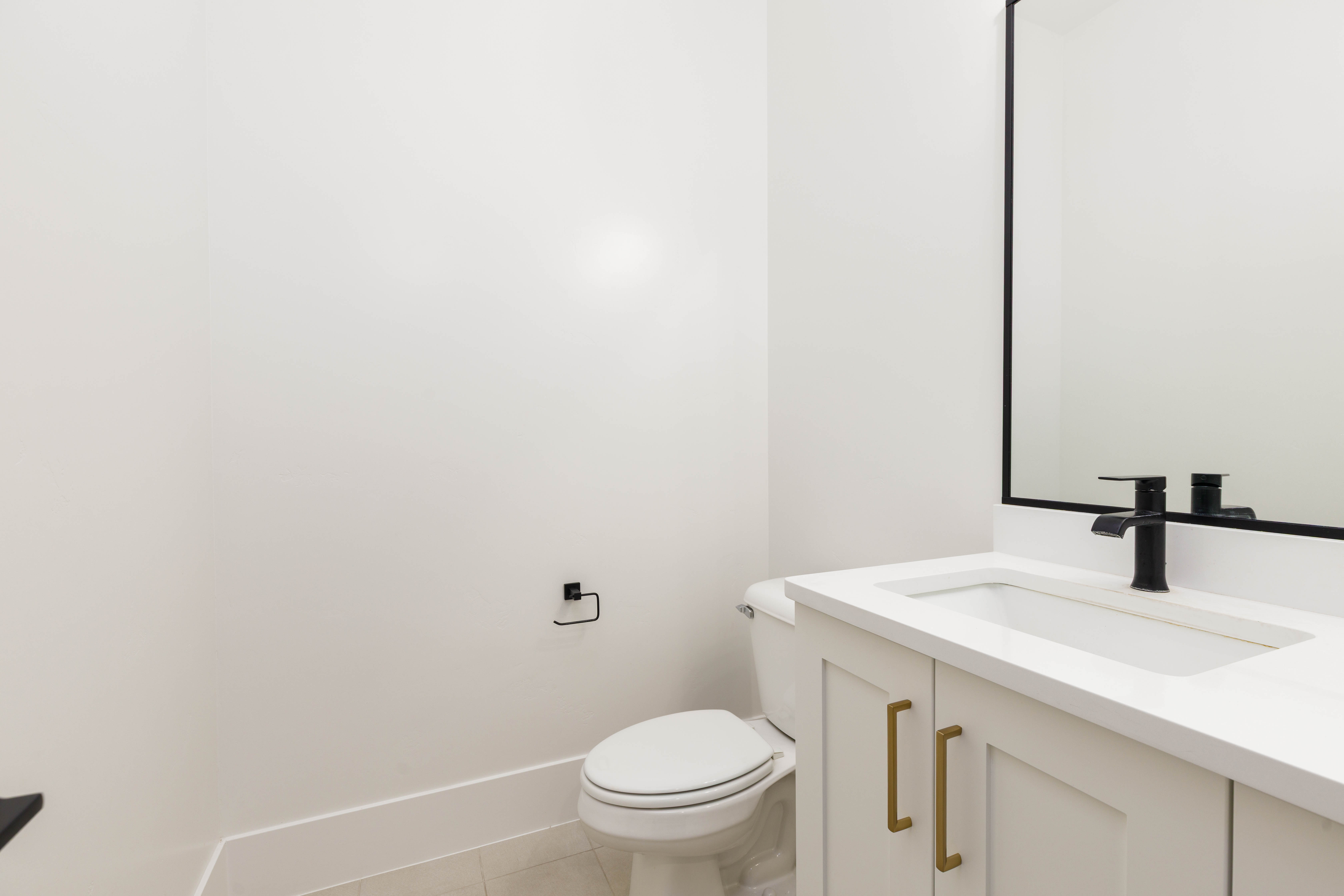 White vanity with a rectangular integrated sink, matte black faucet, and brass-tone hardware