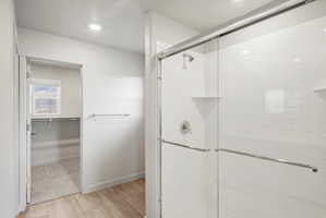 Shower with subway tile surround, integrated shelving, and sliding glass enclosure