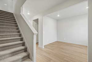 Open room with wood-finish flooring, recessed lighting, and white baseboards