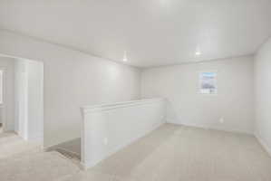 Carpeted upper level lounge with a window featuring horizontal blinds, recessed lighting, and a white wall-mounted railing overlooking a lower level