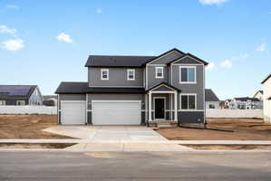 Contemporary two-story exterior featuring gray siding, a covered entry, and a two-car garage with a separate single-car garage