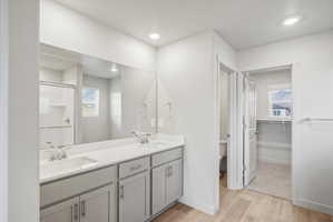Bathroom featuring a dual vanity with light gray cabinetry, white countertops, and chrome fixtures