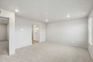 Spacious room featuring light-toned carpeting, recessed lighting, and a window with horizontal blinds