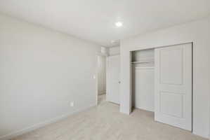 Neutral tone walls with light carpeting, a built-in closet with sliding panel doors, and a recessed ceiling light fixture