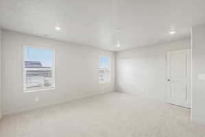 Spacious room featuring neutral carpeting, light-toned walls, and recessed lighting