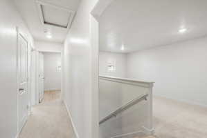 Upper-level hallway featuring a carpeted floor, recessed lighting, and white paneled doors