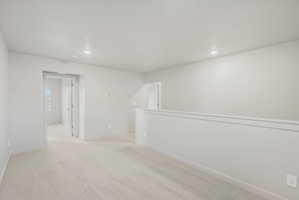 Open loft area with neutral-toned carpeting and light gray wall finishes