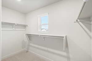 Walk-in closet with carpet flooring, built-in shelving, hanging rods, an integrated window, and recessed ceiling lighting