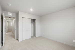 Bedroom featuring light-toned carpeting, neutral wall paint, and a sliding closet door