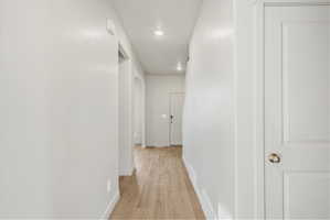 Hallway with wood-finish flooring, recessed lighting, and a neutral color palette