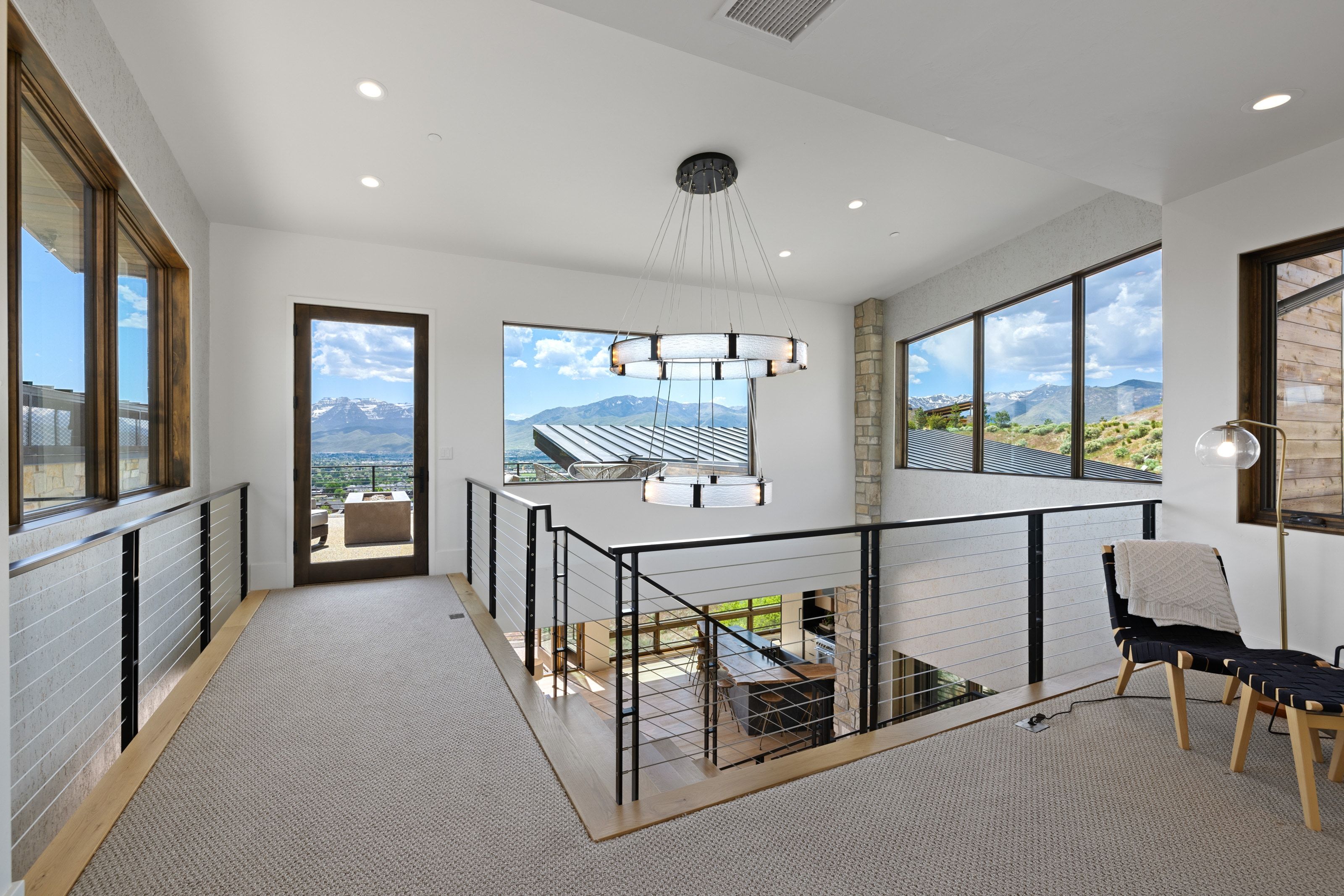 Upper-level landing featuring a contemporary chandelier, recessed lighting, and large windows
