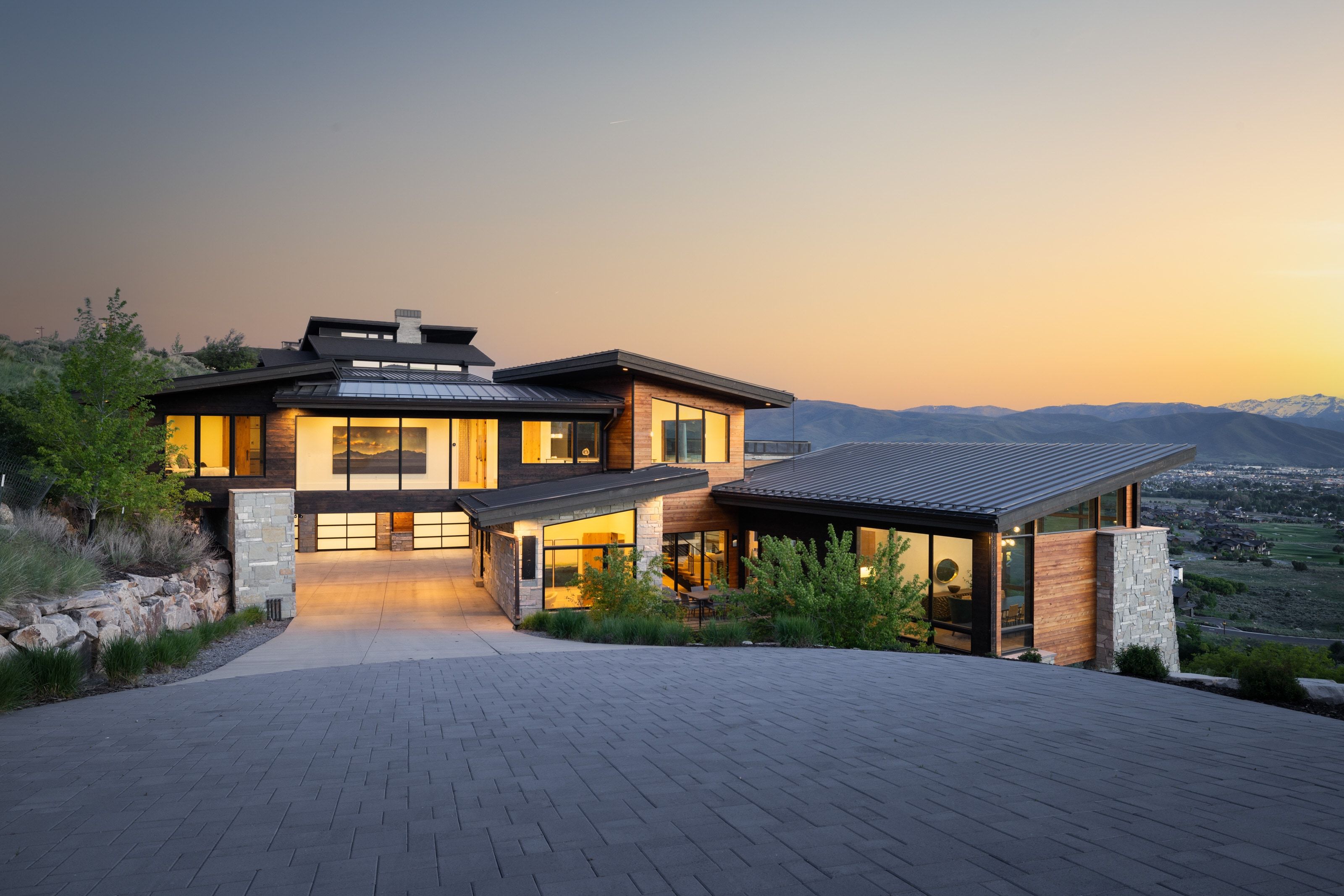 Modern architectural residence featuring a multi-level design, wood-finish siding, and stone accents