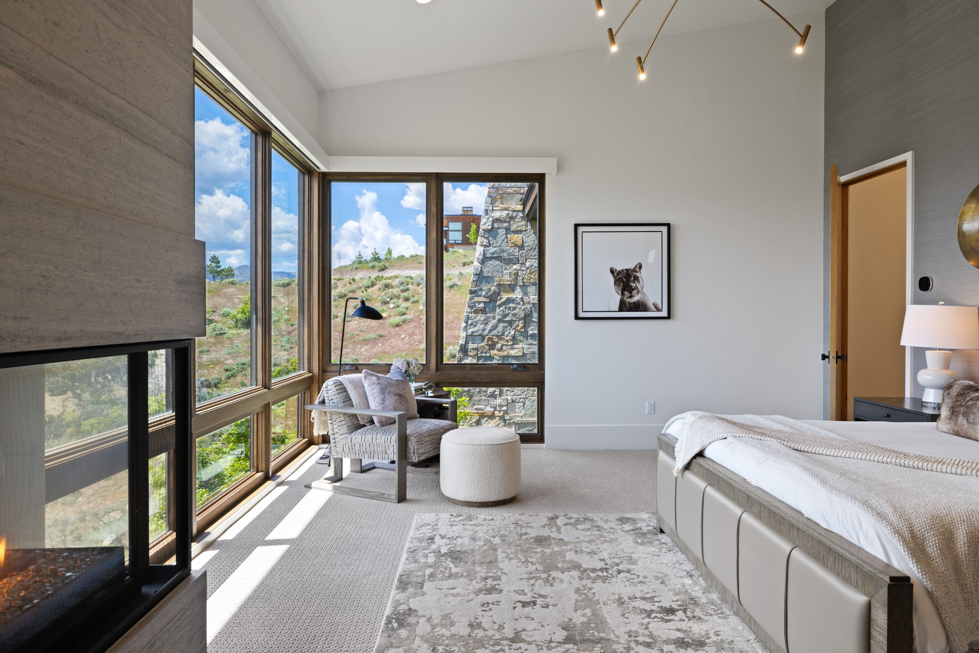 Expansive window wall with natural wood frames, stone architectural features, and an integrated fireplace