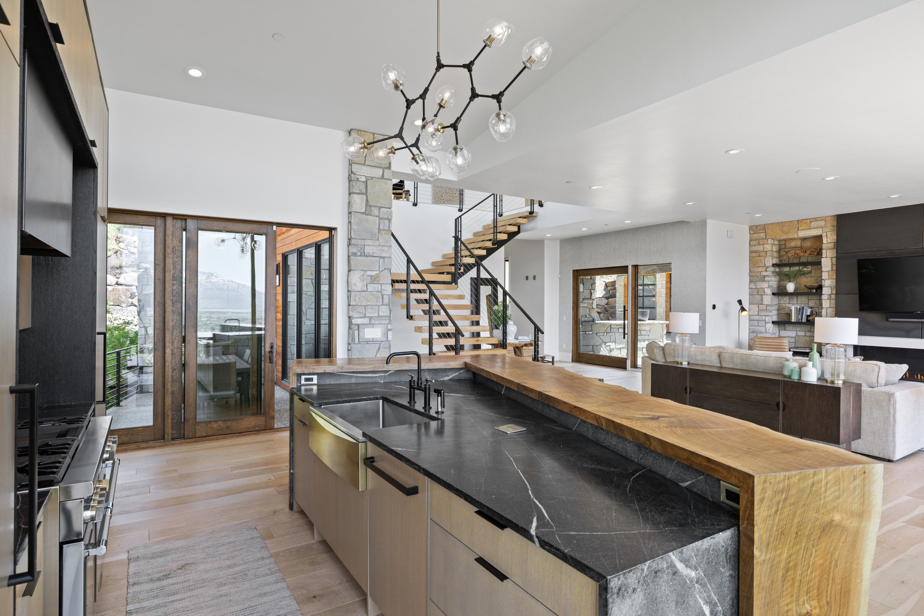 Modern kitchen island featuring a black veined countertop, an undermount sink, and a live-edge wood breakfast bar