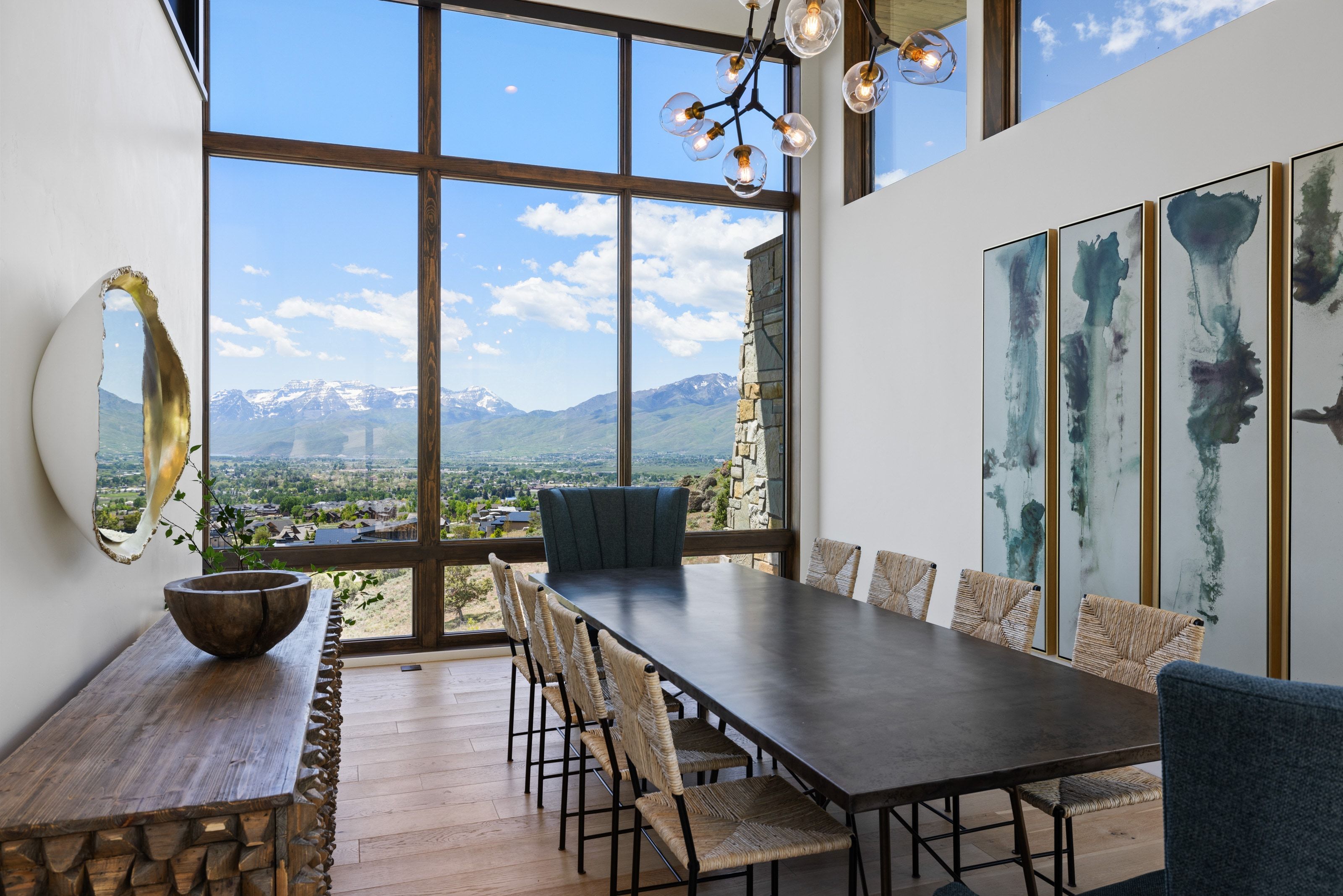 Two-story window wall with dark wood trim framing mountain and valley scenery