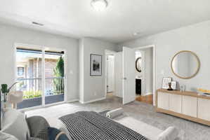 Bedroom featuring a sliding glass door leading to a balcony, light gray wall paint, and gray carpet flooring