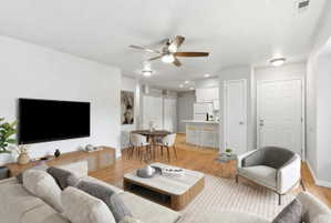 Open-concept living area featuring wood-finish flooring and a ceiling fan with integrated lighting