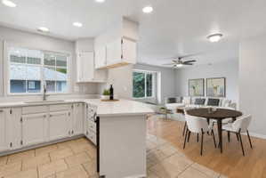 Open-concept kitchen featuring white cabinetry, light-toned countertops, and a stainless steel sink with a gooseneck faucet