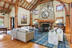 Great room featuring a prominent stone fireplace with a substantial wood mantel, exposed wood beam ceiling, and skylights