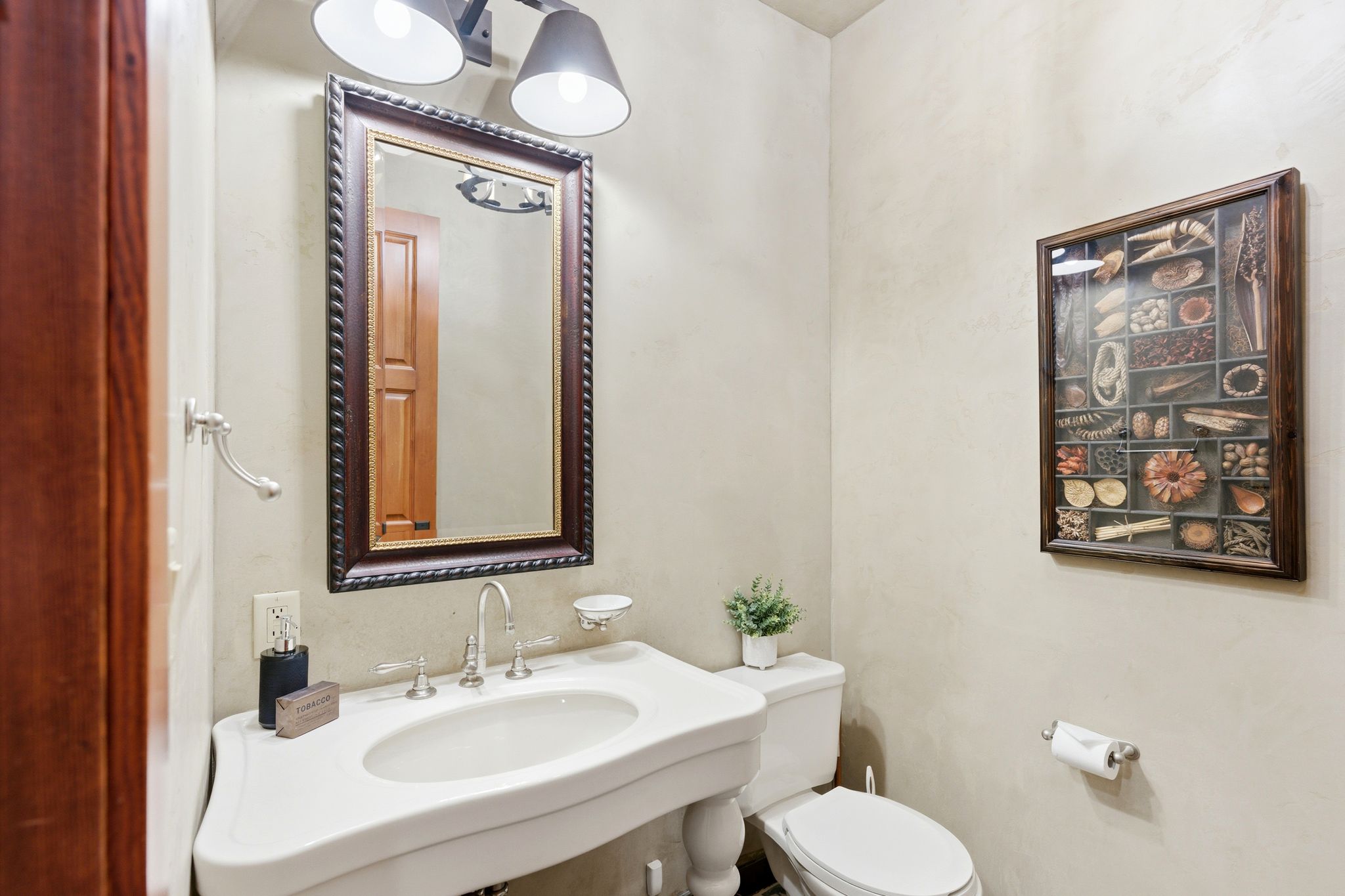 Pedestal sink with polished chrome faucet and a framed mirror