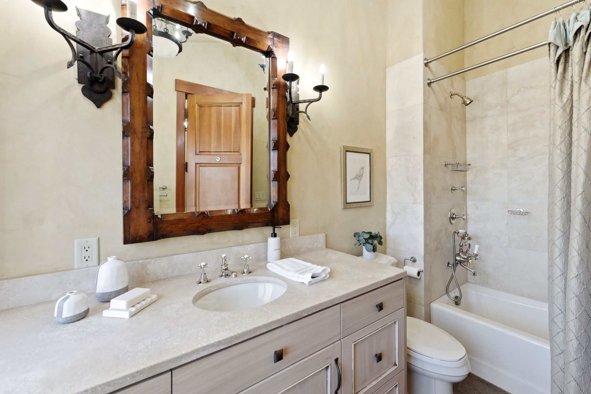 Bathroom vanity featuring an integrated sink with brushed nickel fixtures, a light-toned countertop, and a decorative wood-framed mirror