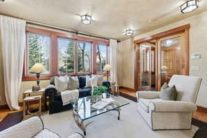 Living area featuring a wall of multi-pane windows with wood trim, hardwood flooring, and a pair of glass-paned French doors with wood framing