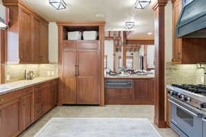 Gourmet kitchen featuring rich wood cabinetry, stone countertops, integrated panel-ready refrigerator, a commercial-style range, and built-in microwave drawer