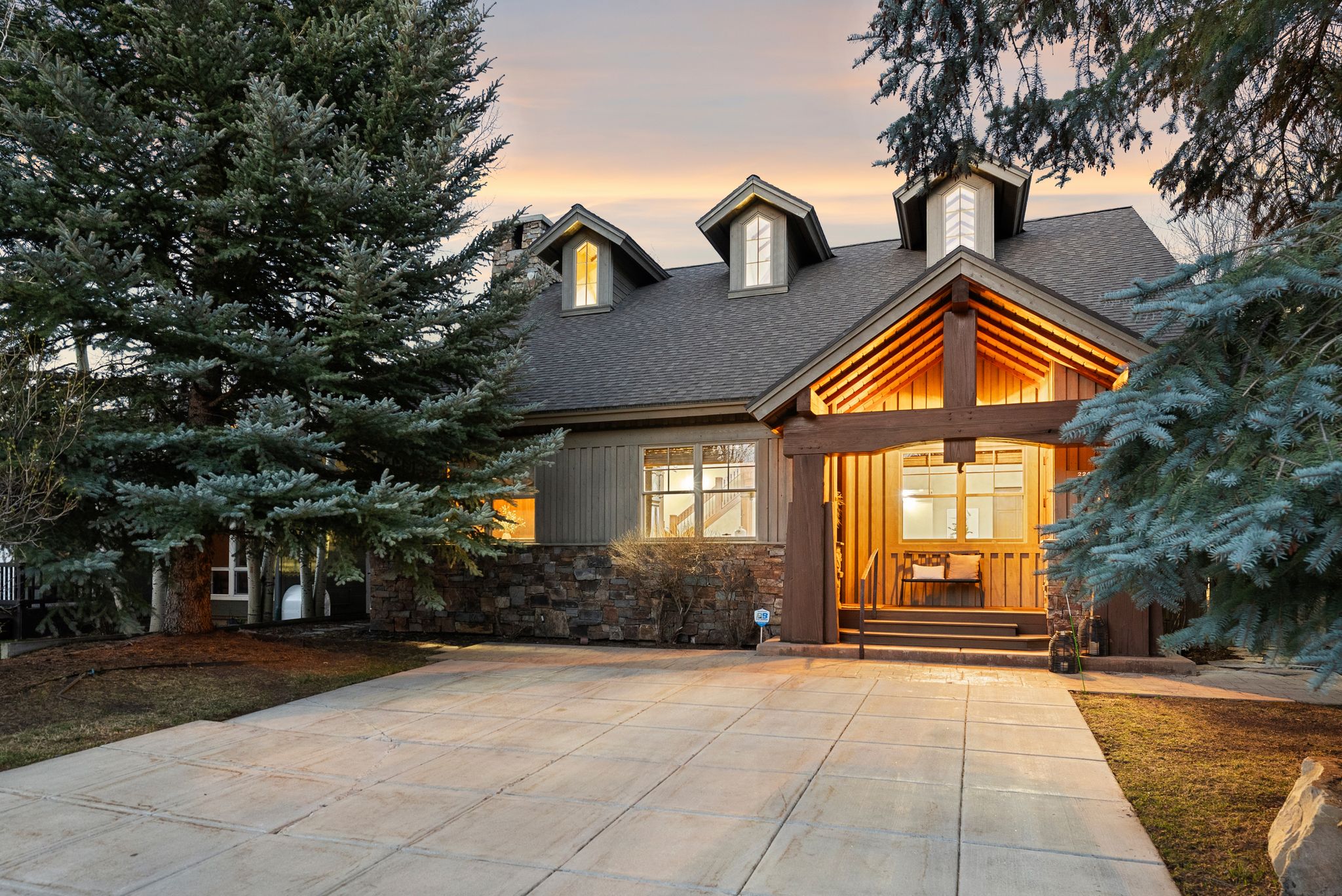 Architectural timber-frame entryway with a stone accent facade and multiple dormer windows