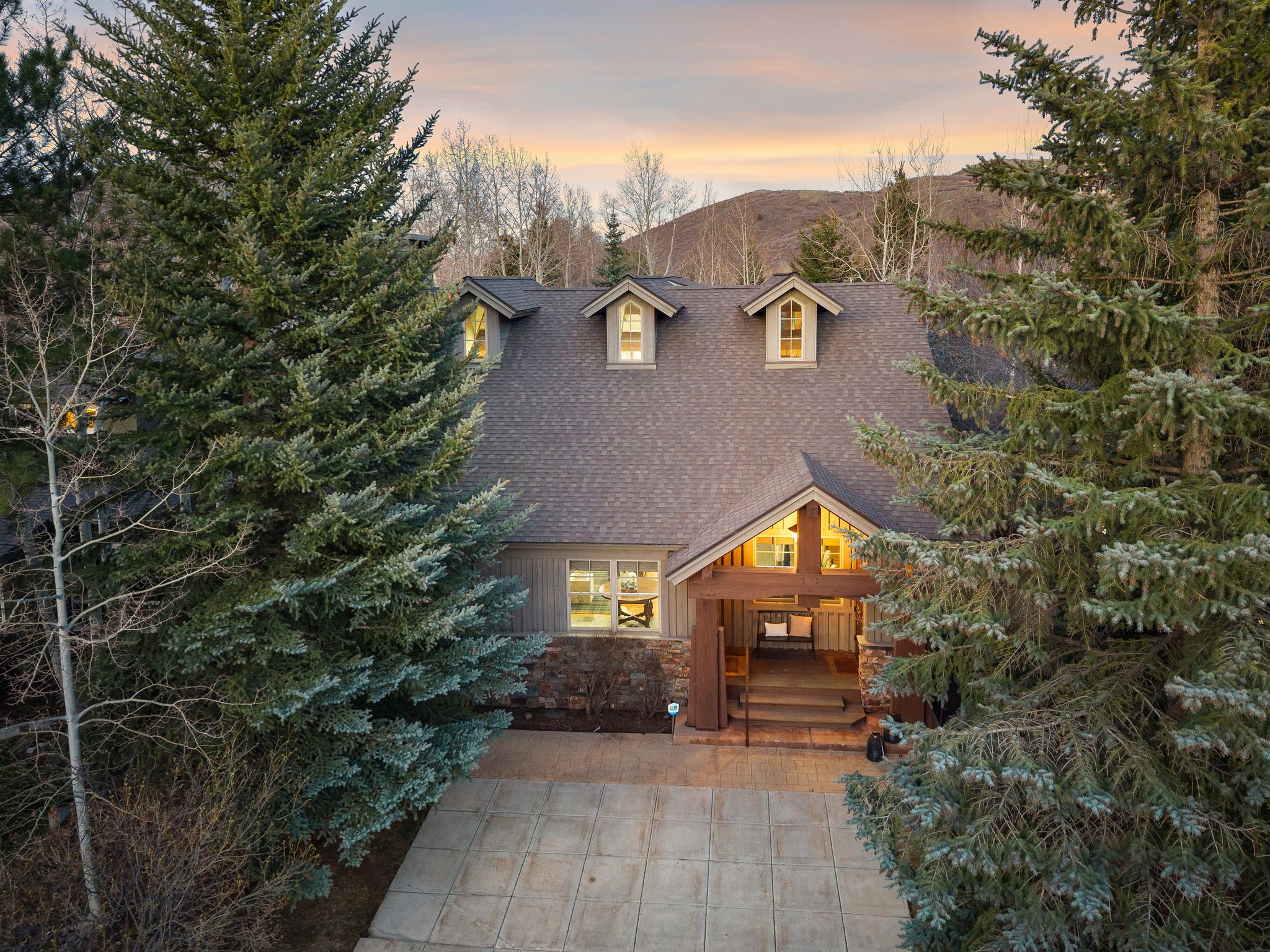 Craftsman-style exterior with a gabled roof, three dormer windows, and a covered porch entry featuring exposed wood beams