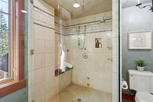 Glass-enclosed shower with ceramic tile surround, recessed niche, built-in bench, and dual shower fixtures