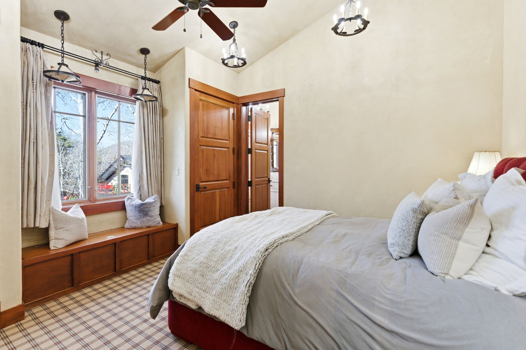 Window seat with storage cabinetry, wood-framed casement windows, and plaid carpet