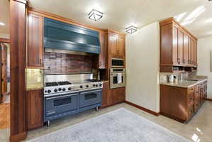 Professional-grade range with a double oven, a custom dark blue range hood, and a brick-patterned backsplash