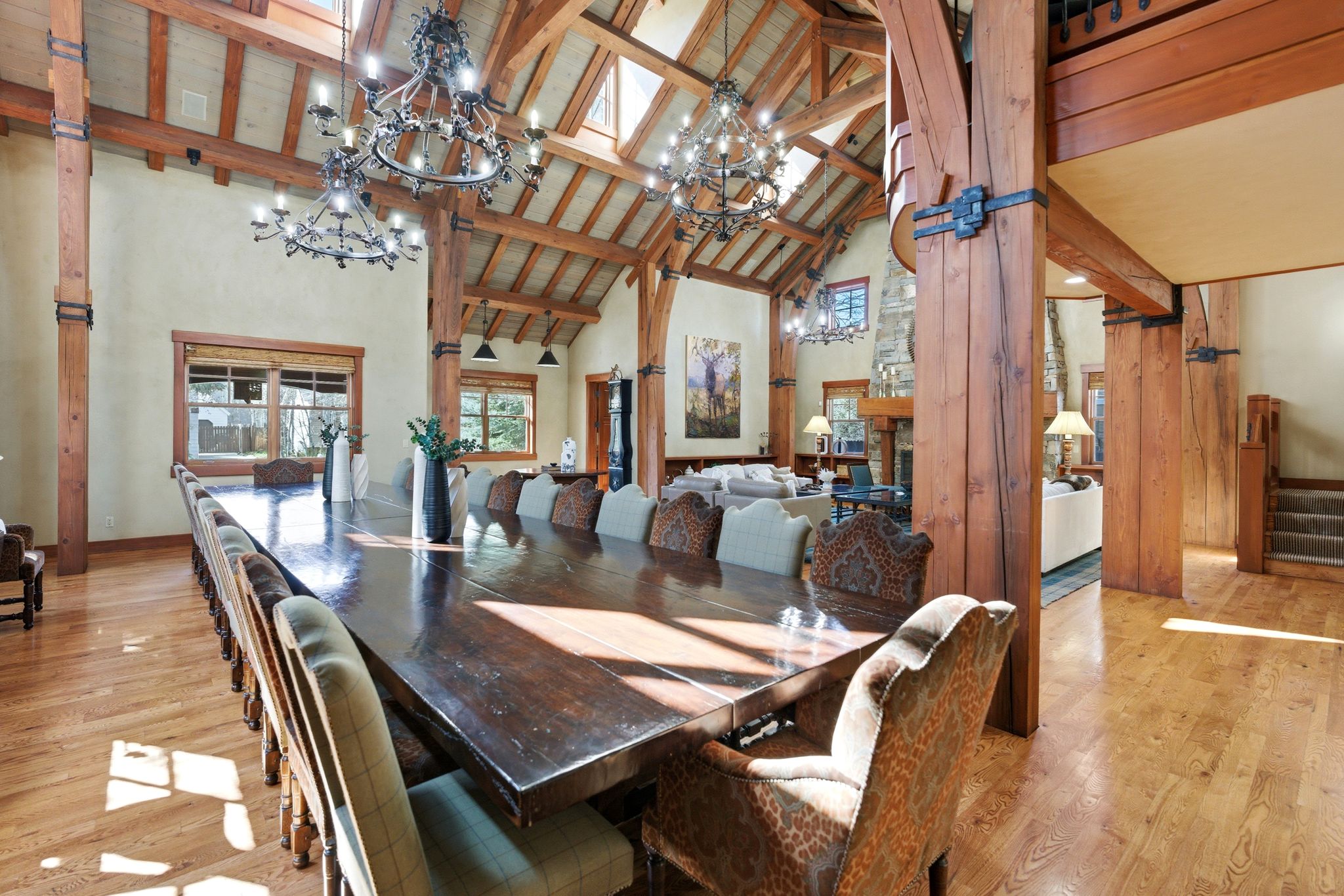 Expansive dining area featuring a vaulted wood-beam ceiling, multiple decorative chandeliers, skylights, and wood-finish flooring