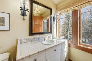 Bathroom vanity featuring a tiled countertop, undermount sink, and traditional fixtures