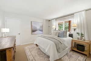 Carpeted bedroom with a large window, a solid panel door, and wall-mounted sconces
