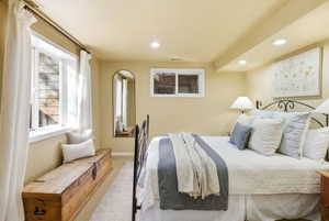 Recessed lighting illuminates this room, featuring a large window with white curtains and a smaller egress window