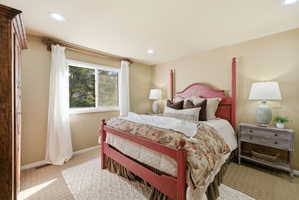 Recessed lighting illuminates this room featuring a large window, neutral wall paint, and textured carpeting