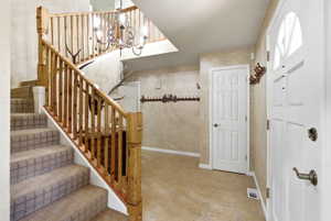 Entry foyer featuring a wood-finish staircase with carpeted treads and natural wood balusters