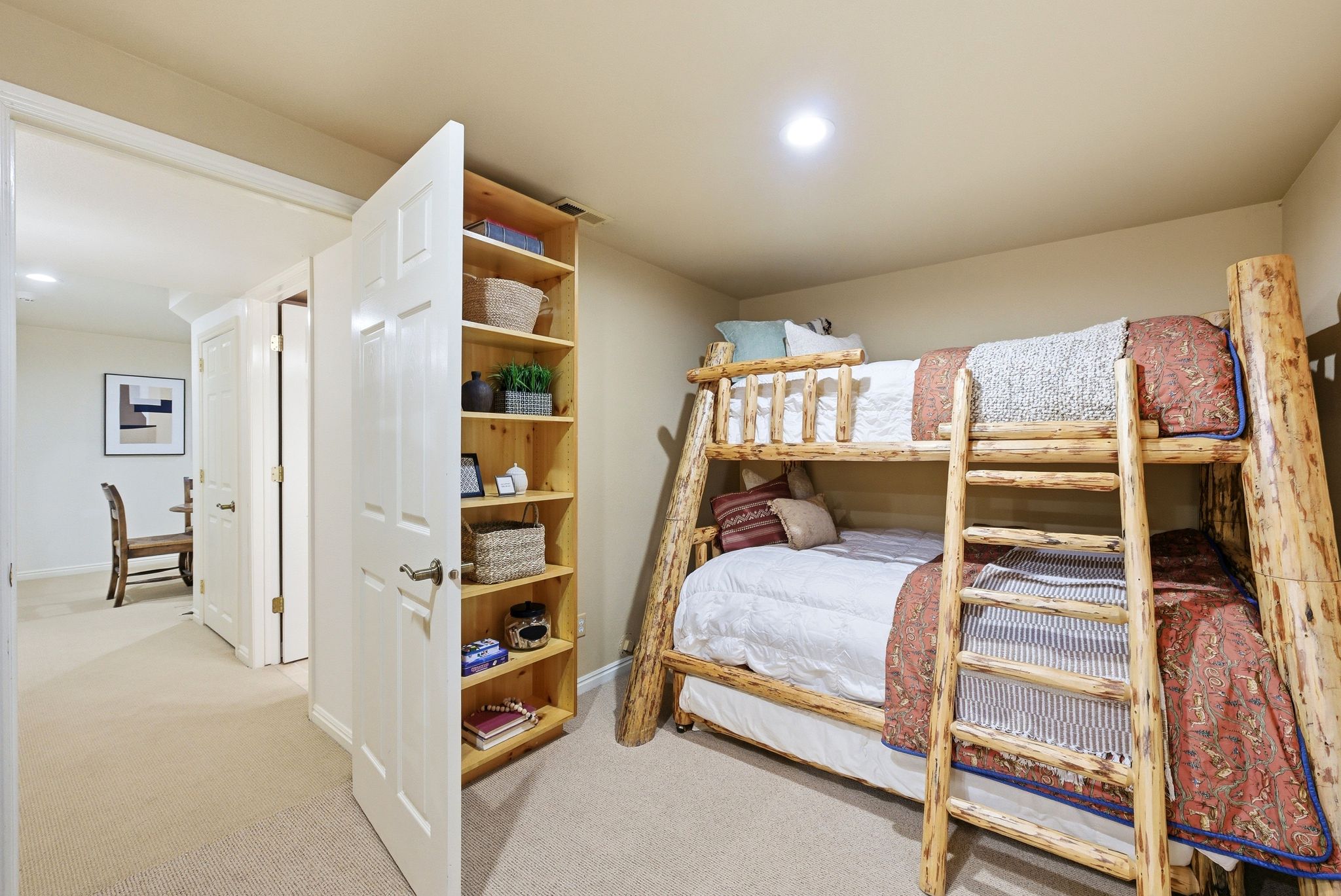 Recessed lighting illuminates a carpeted bedroom featuring a built-in wooden shelving unit