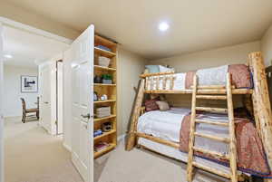 Recessed lighting illuminates a carpeted bedroom featuring a built-in wooden shelving unit