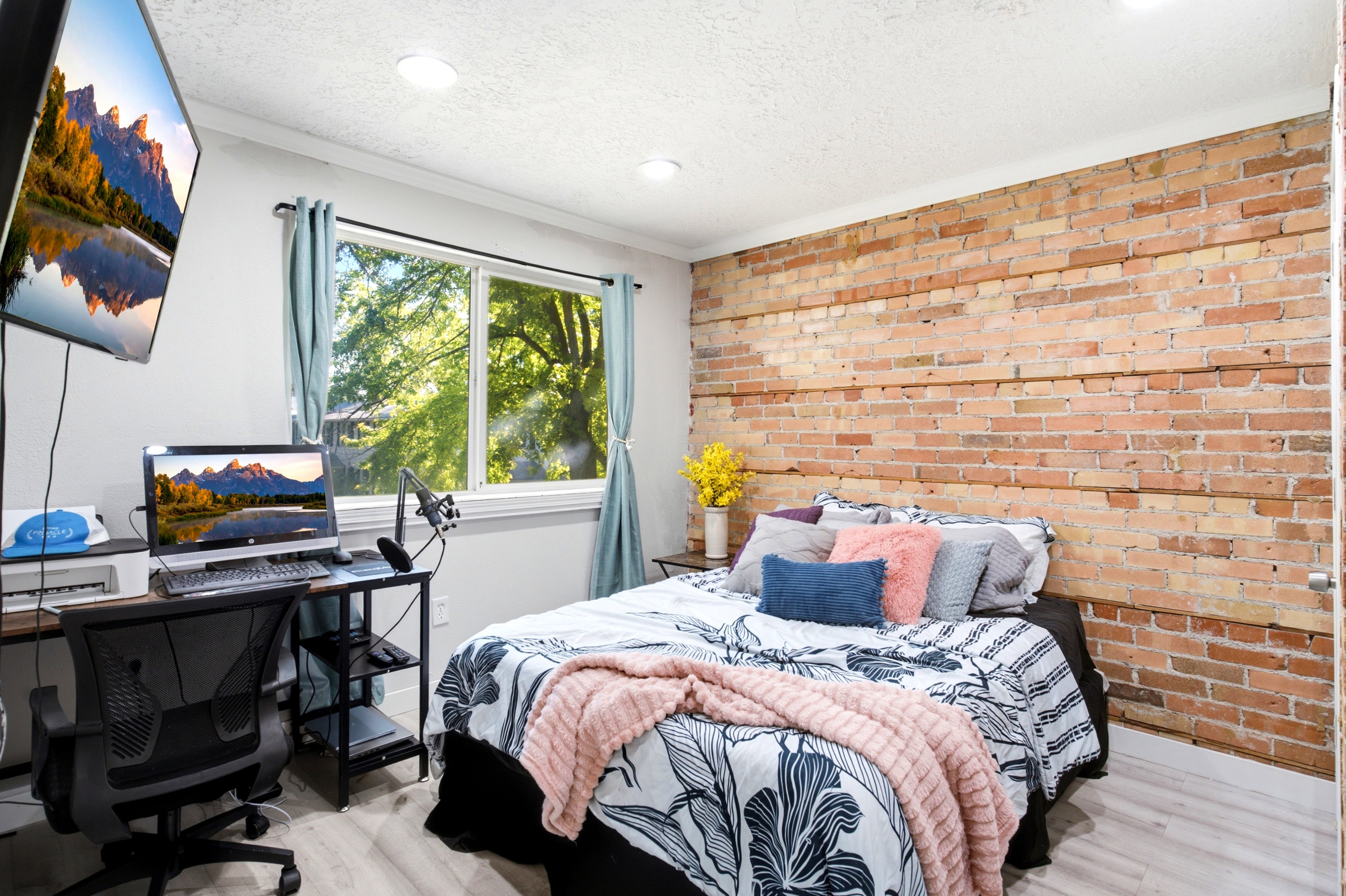 Exposed brick accent wall with recessed ceiling lighting, a large window with natural light, and wood-finish flooring