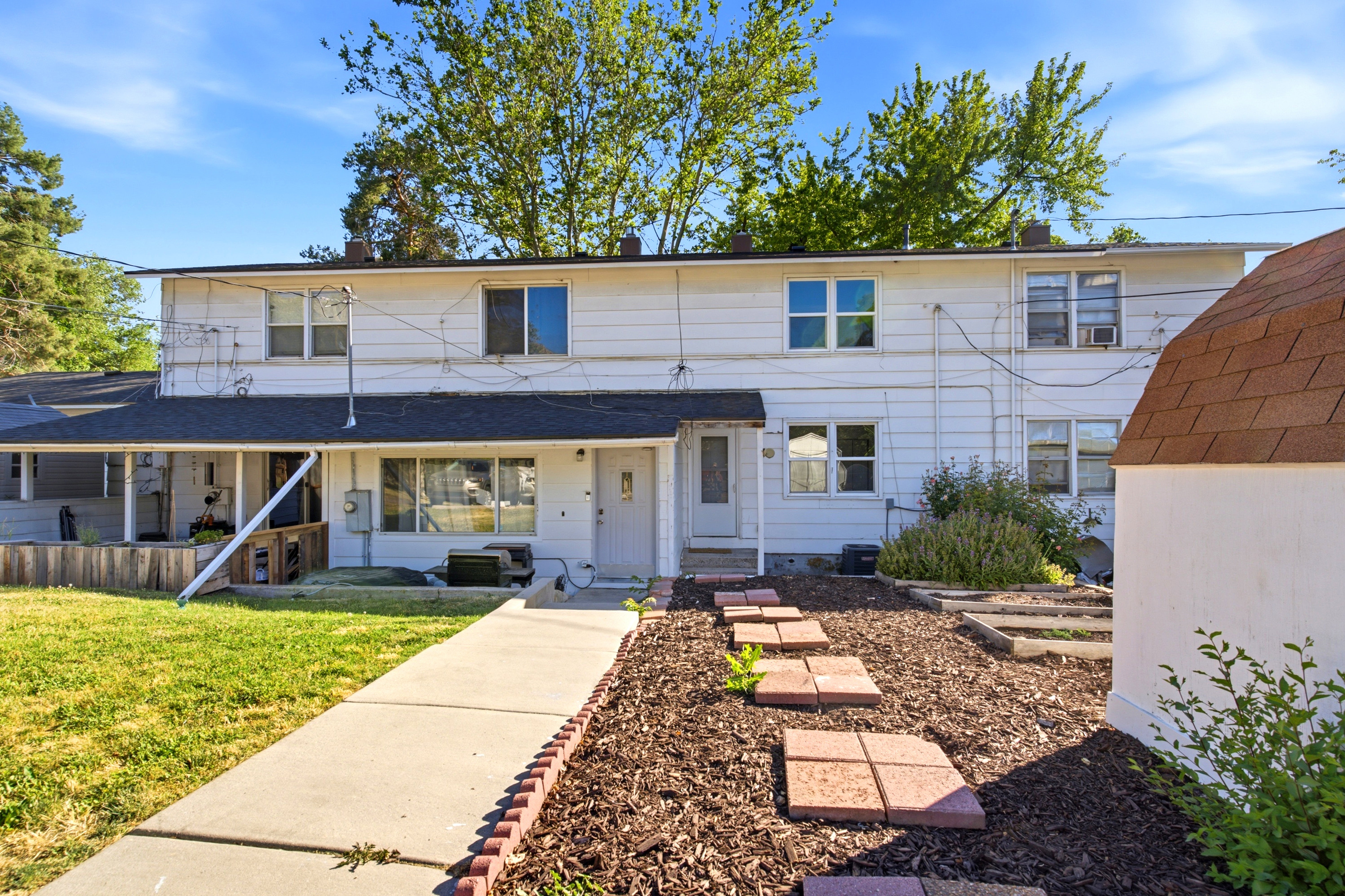 Two-story white exterior building with multiple windows, a covered porch, and a sidewalk leading to the entrance
