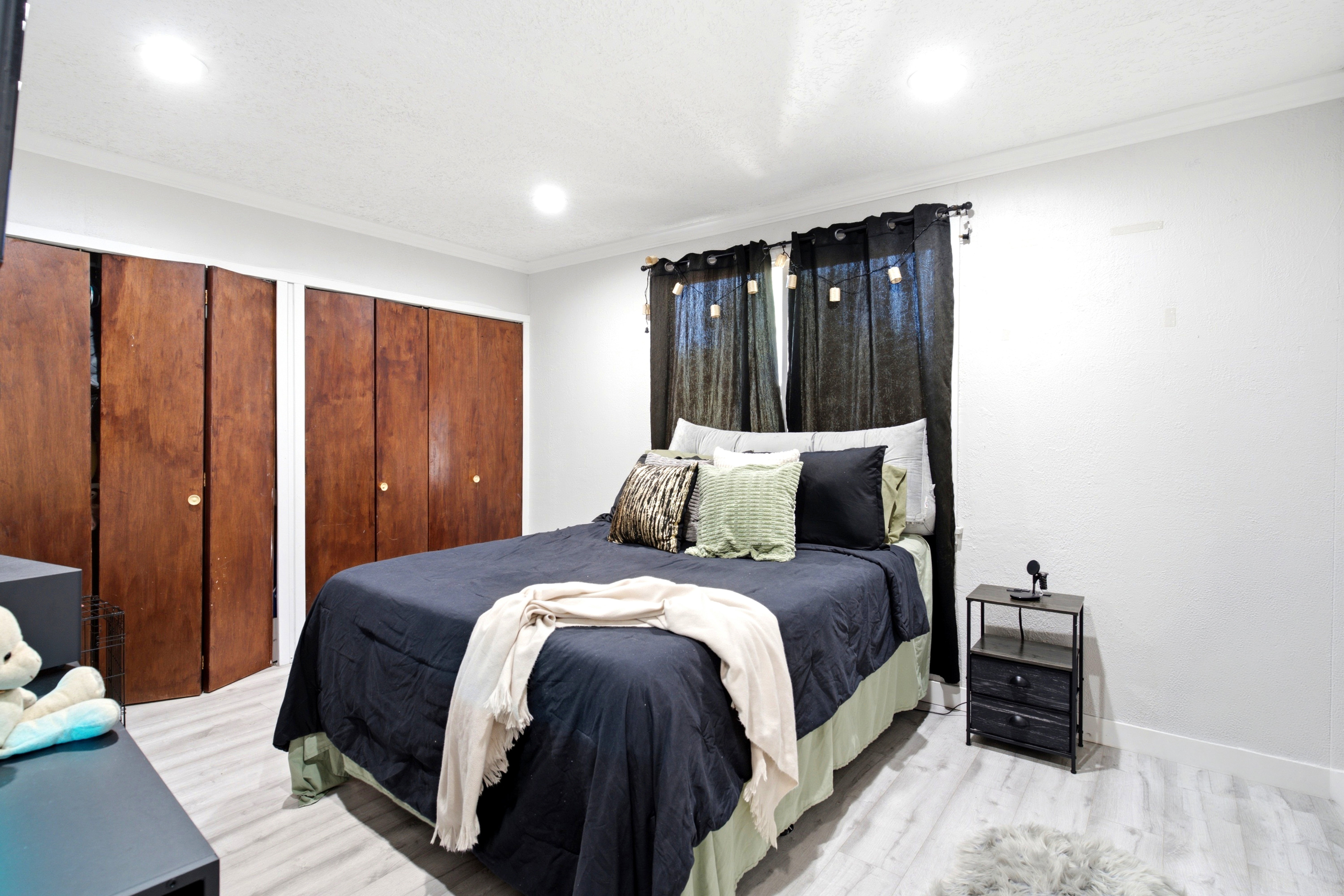Bedroom featuring wood-finish bi-fold closet doors, crown molding, recessed ceiling lighting, and wood-finish flooring