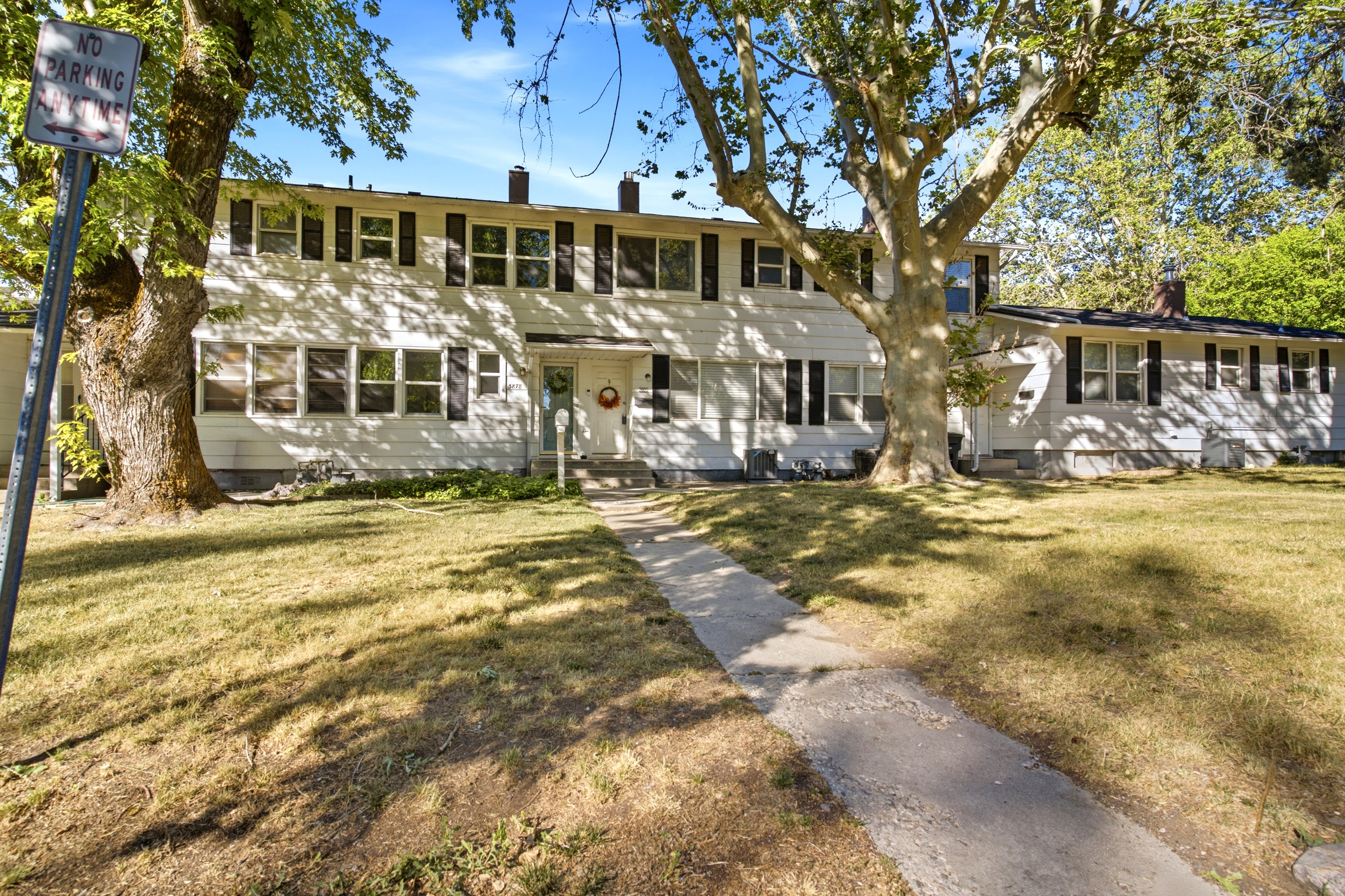 White two-story exterior with dark window shutters, multiple windows providing ample natural light, and a prominent front walkway