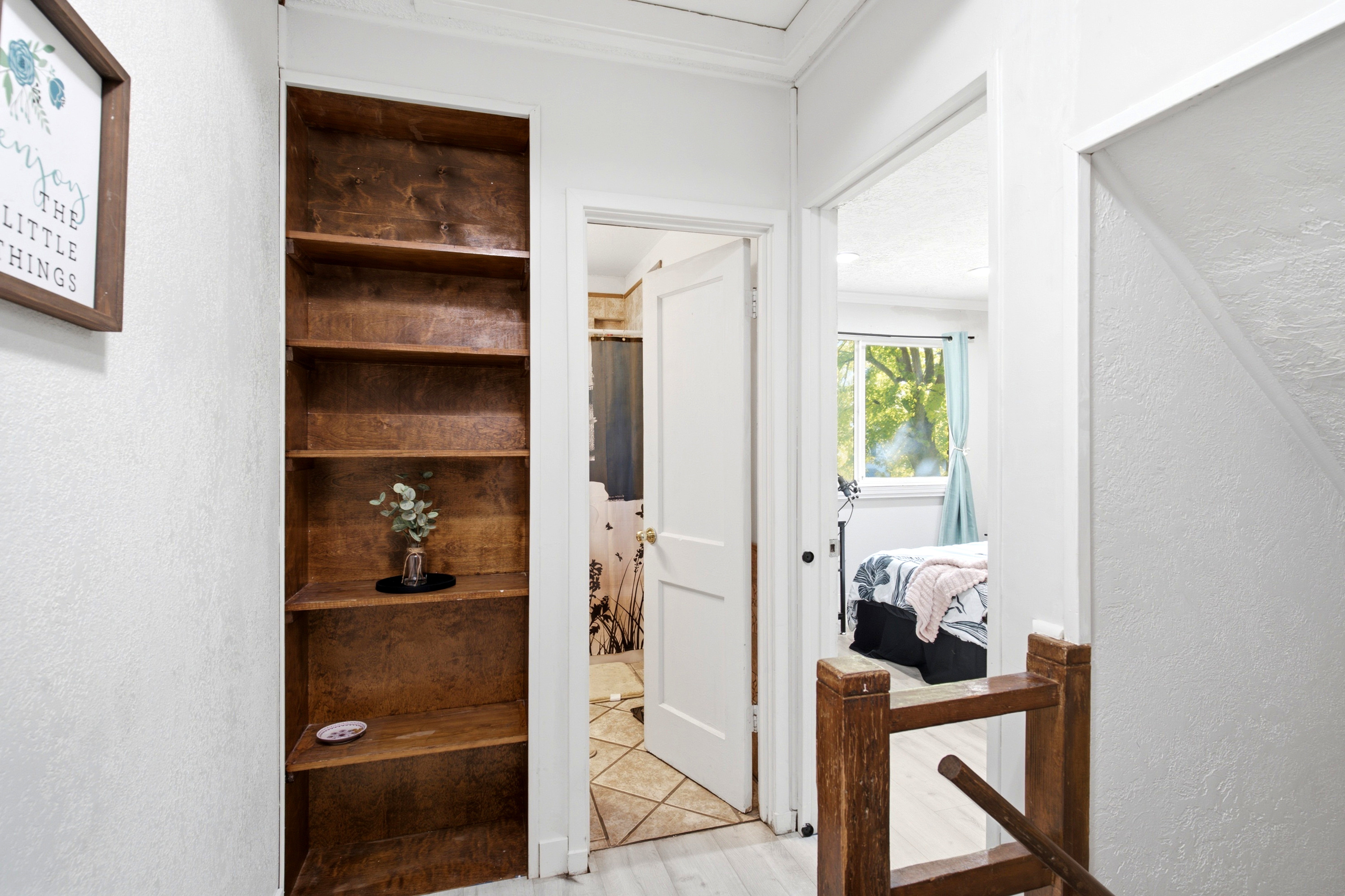 Built-in wood shelving unit with multiple tiers, white walls, and wood-finish flooring